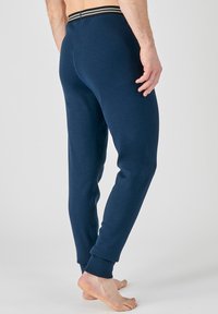 Pantalones de chándal azul marino hechos de una mezcla de algodón, con una cintura elástica a rayas y puños en los tobillos ajustados.