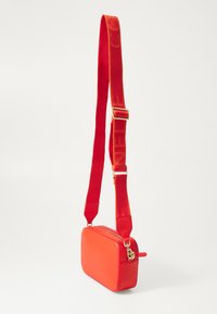 Borsa a tracolla rossa con finitura testurizzata, forma rettangolare e ampia tracolla rossa con motivi del logo. Accenti in hardware dorato.