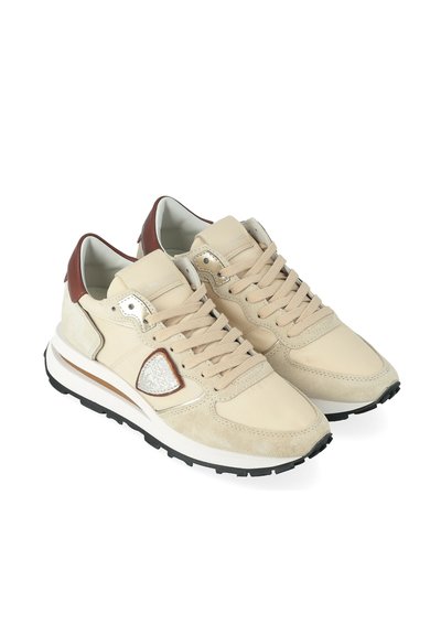 Sneakers bassi beige e marroni con lacci, patch logo testurizzato sul lato e suole in gomma nera, mostrati da un'angolazione frontale su uno sfondo bianco.