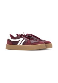 Zapatillas burdeos con acentos blancos, parte superior de tela, suela de goma, puntera redondeada y cordones planos. Acabado texturizado con detalle del logo en un lado.