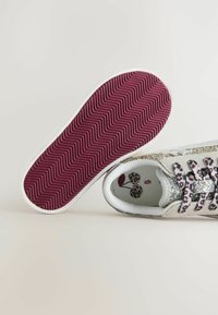 Zapatilla cubierta de brillantina con cordones de estampado de leopardo, suela blanca y una parte inferior de goma morada texturizada con un patrón de zigzag.