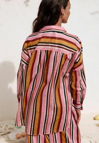 Camicia a maniche lunghe a righe con tonalità di rosa, arancione e marrone, dotata di colletto con bottoni e dettaglio arricciato sul retro.