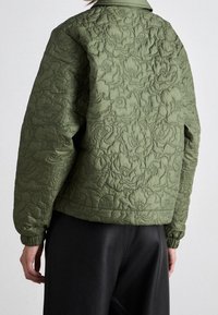 Kurtka bombowiec pikowana w oliwkowym kolorze z kwiecistym wzorem, posiadająca kołnierz, ściągacze oraz luźny krój. Miękka tekstura i trwały materiał.
