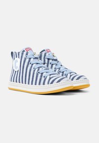 Sneakers alta in tela a righe blu e bianche con suola gialla, dotate di lacci blu e un logo circolare sul lato.
