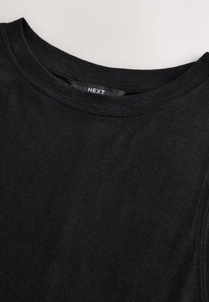 Mustast puuvillast T-särk, millel on ümmargune kaelus, lihtne disain ja sile pind. Kaela tagaküljel on nähtav tekstimärk "NEXT".