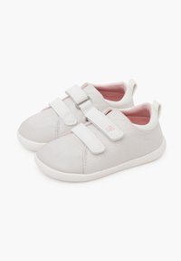 Zapatillas de lona gris claro con dos tiras de velcro. Suelas de goma blancas, interior en color rosa y un acabado texturizado sutil en el material superior.
