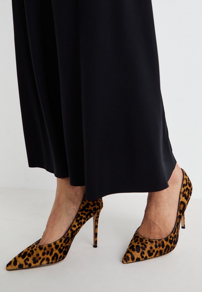 Leopardenmuster High Heels aus strukturiertem Stoff, mit spitzem Zehendesign und schlankem Stiletto-Absatz, kombiniert mit einem fließenden schwarzen Kleid.