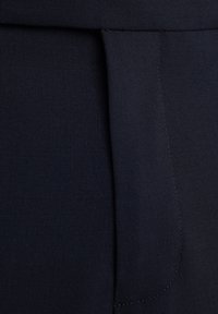 Marinblått tyg med en jämn textur har en platt midja och vertikala sömnadsdetaljer. Minimalistisk design utan synlig metallic.