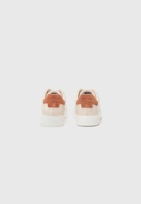 Sneakers in pelle beige con accentuazione in suede marrone sul tallone e suola in gomma bianca. Presentano un logo impresso sul tallone e un design a profilo basso.