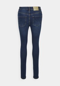 Jeans ajustados em denim azul escuro, com uma cintura de altura média, dois bolsos traseiros e uma textura suave. Costuras desbotadas ao longo das costuras.