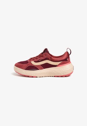 Zapatilla atlética roja y beige con parte superior de malla y ante, suela gruesa y texturizada, puntera redonda y un sutil detalle de logo.