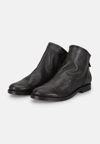 Botas de tobillo de cuero perforado negro con punta redonda, tacón bajo y una lengüeta en la parte trasera para facilitar su puesta.