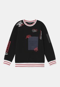 Musta collegepaita, jossa on punavalkoraidalliset ribbineulotut hihansuut ja pääntie, graafisia painokuvia sekä keskellä neliönmuotoinen kangasmerkki, jossa lukee "NINETEEN EIGHTY ONE."