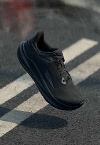 Scarpa sportiva nera con tomaia texturizzata, chiusura con lacci e suola imbottita. Presenta un design elegante e un logo prominente di lato.
