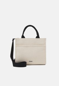 Beige rektangulær lærred skuldertaske med sorte håndtag, en lang sort rem, frontlomme og "ZIGN" logo nederst i midten.