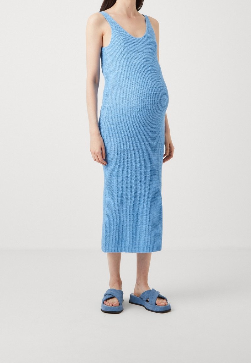 Abito a coste di un blu chiaro con una silhouette aderente e spalline larghe, abbinato a comode ciabatte blu chiaro con fasce incrociate.