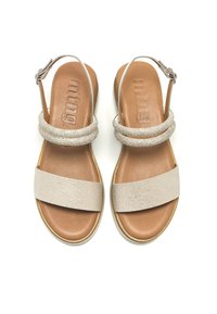 Sandali slingback beige e argento con una parte superiore testurizzata, due fasce piatte e un plantare imbottito marrone. Fibbia regolabile alla caviglia.