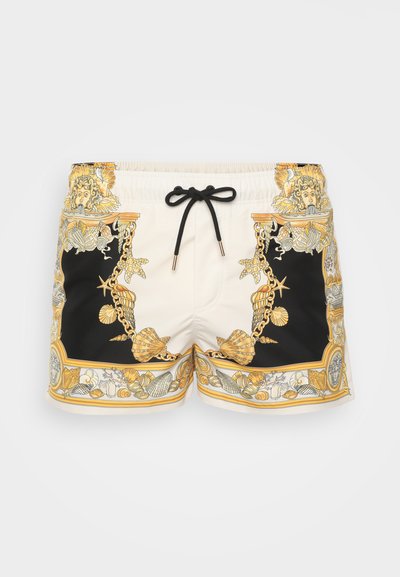 Shorts de bain dans une combinaison de couleurs crème et noire, ornés d'un motif décoratif de coquillages dorés et d'un cordon noir à la taille.