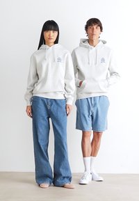 Light gray hoodies with front pockets and drawstrings, paired with blue denim pants on the left and blue shorts on the right.