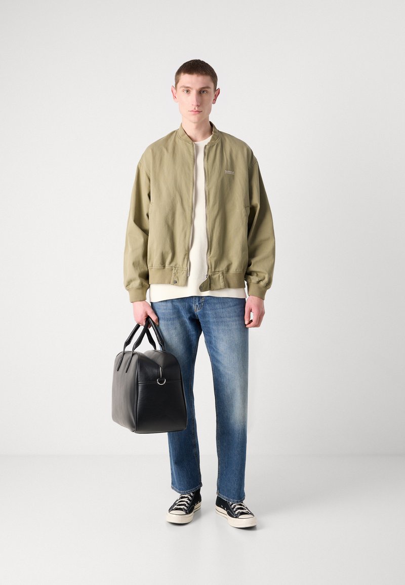 Olivenfarbener Bomberjacke, weißes Hemd, blaue Jeans, schwarze Ledertasche und marineblaue Sneakers. Lässiges Outfit mit lockerer Passform und minimalistischen Design.