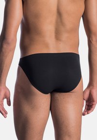 Black swim briefs with a smooth, stretchy fabric. Features a high-cut design, seamless waistband, and minimal rear coverage.