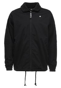 Czarna kurtka z zamkiem z przodu, kołnierzem z polaru, elastycznymi mankietami, ściągaczem u dołu oraz bocznymi kieszeniami. Posiada logo na piersi.