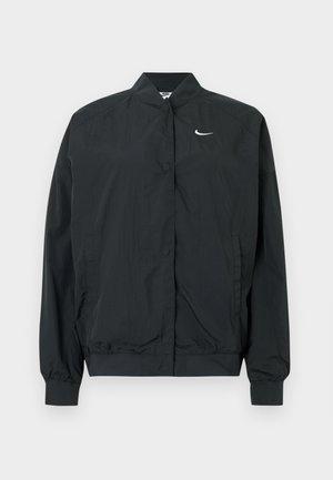 Musta Nike-takki, jonka kevyt ja sileä pinta. Takissa on korkea kaulus, edessä nepparikiinnitys ja pieni valkoinen logo rinnassa.