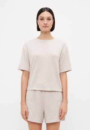 Ljusbeige bomullsblandning loungewear-set som består av en avslappnad kortärmad topp och matchande shorts med sidfickor och mjuk textur.