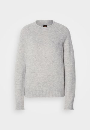 Lys grå genser laget av mykt strikket materiale. Har rund hals, ribbede mansjetter og en avslappet passform med raglanermer.
