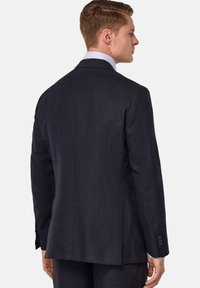 Veste de costume en lin bleu marine foncé avec des revers crantés, une fente simple et des accents de poignets boutonnés. Texture lisse et coupe ajustée.