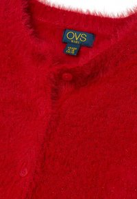 Rode harige cardigan met een ronde halslijn, twee knopen en een label met de tekst "OVS kids", gemaakt van een zachte, gestructureerde stof met een lichte glans.