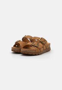 Tan semskede sandaler med to justerbare stropper med bronsefargede spenner, en formet korkfotbehag, og en teksturert gummiyttersåle.