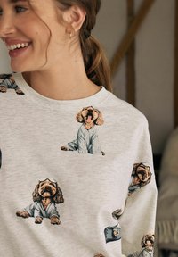 Felpa grigia chiaro con scollo a girocollo, caratterizzata da una stampa ripetuta di cani in pigiama. Tessuto morbido con colletto e polsini a costine.