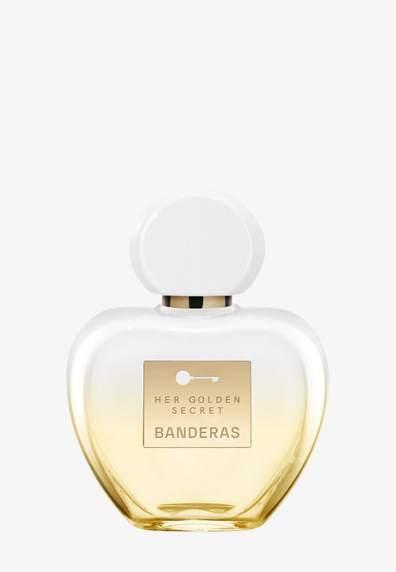 Transparent glas parfumflaske med hvid rundet hætte, gylden gradientbund og gylden label med teksten "Her Golden Secret Banderas."