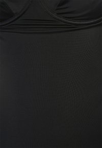 Maiô preto de uma peça com uma textura suave e elástica. Apresenta um decote em forma de colher e detalhes franzidos na área do busto.
