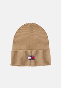 Gorra de punto color marrón con un diseño acanalado y un dobladillo doblado. Presenta un parche con el logo en azul, rojo y blanco en la parte frontal.