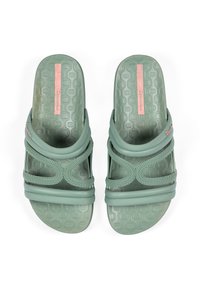 Green rubber slide sandals with a textured pattern, featuring two looped straps and a pink logo label across the top.