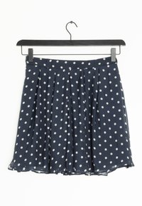 Mörkblå midja med prickar, tillverkad av lättviktig tyg med veck och en något utsvängd silhuett. Hänger från en svart klädhängare.