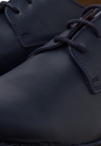 Scarpe in pelle blu navy con una texture liscia, caratterizzate da una punta arrotondata, sottili dettagli di cucitura e lacci scuri.