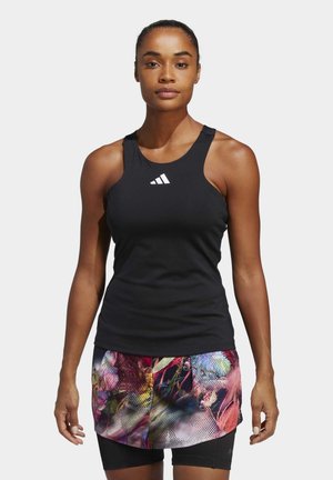 Débardeur de sport noir avec un col rond et un logo blanc, associé à un short à imprimé floral coloré. Présente une coupe ajustée.