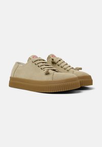 Beżowe zamszowe sneakersy z okrągłymi noskami, okrągłymi sznurówkami i grubą gumową podeszwą w kontrastowym kolorze tanowym, z subtelnymi detalami w szyciu.