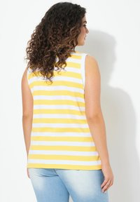Gul och vit randig ärmlös topp, tillverkad av lättviktig tyg med rund halsringning och avslappnad passform. Slät textur.