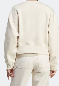 Krämfärgad sweatshirt med sänkta axlar, ribbade manschetter och en kortad nederkant, tillsammans med matchande högmidjade byxor med bakfickor.