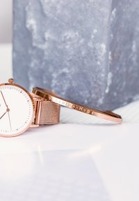 Montre en or rose avec un cadran blanc, bracelet en maille et index numériques. Accompagnée d'un bracelet en or rose assorti avec une gravure "Victoria Hyde".