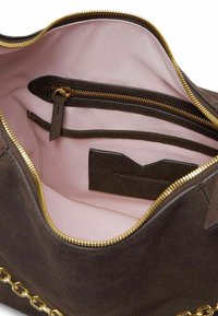Interno di borsa in suede marrone con fodera rosa, cerniera dorata, tasca con cerniera e fessure per carte. Presenta un dettaglio a catena sull'esterno.