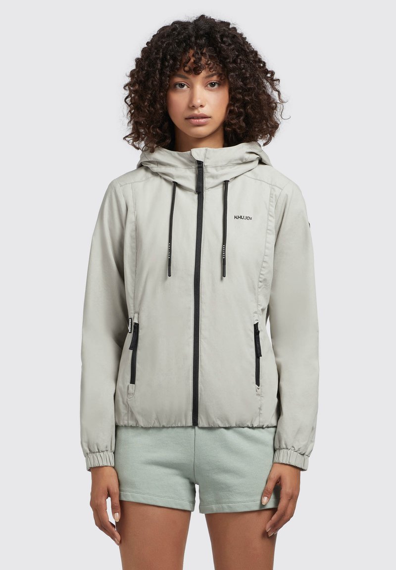 Lichtgrijze, ritssluitingjack met capuchon, zwarte accenten en elastische manchetten. Heeft zijzakken en een lichtgewicht, gladde textuur.