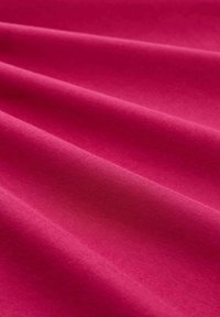 Fuchsia-Stoff mit einer glatten, matten Textur, die subtile Wellen und Falten aufweist und die lebendige Farbe sowie das leichte Design hervorhebt.