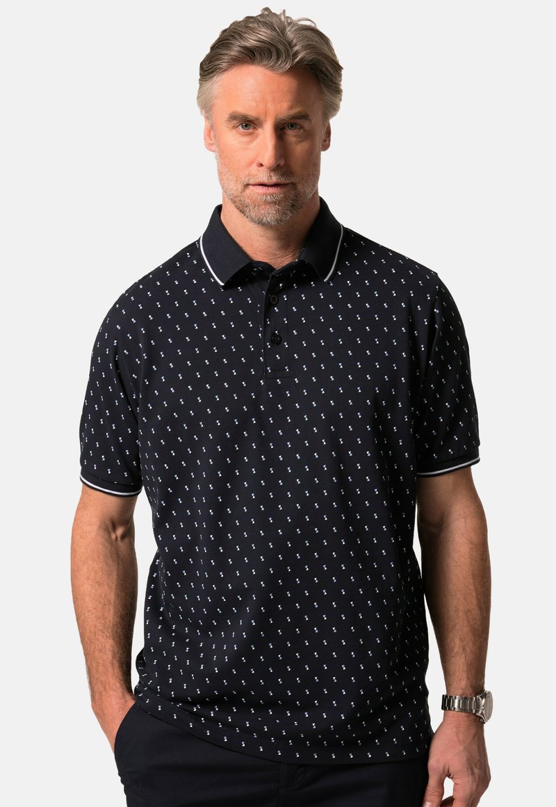 Námornická polo košile v námořnické modré barvě s bílou vzorovou kotvou, krátkými rukávy, třemi knoflíky a kontrastním límcem s bílým lemem.