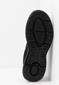 Schwarze Sportlaufschuhsohle aus strukturiertem Gummi für Grip. Verfügt über kreisförmige Muster und tiefe Rillen für Flexibilität und Traktion.