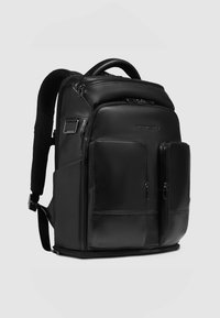 Zwarte leren rugzak met meerdere ritsvakken, gewatteerde riemen en een handvat aan de bovenkant. Heeft een strak, gestructureerd ontwerp en een gladde textuur.